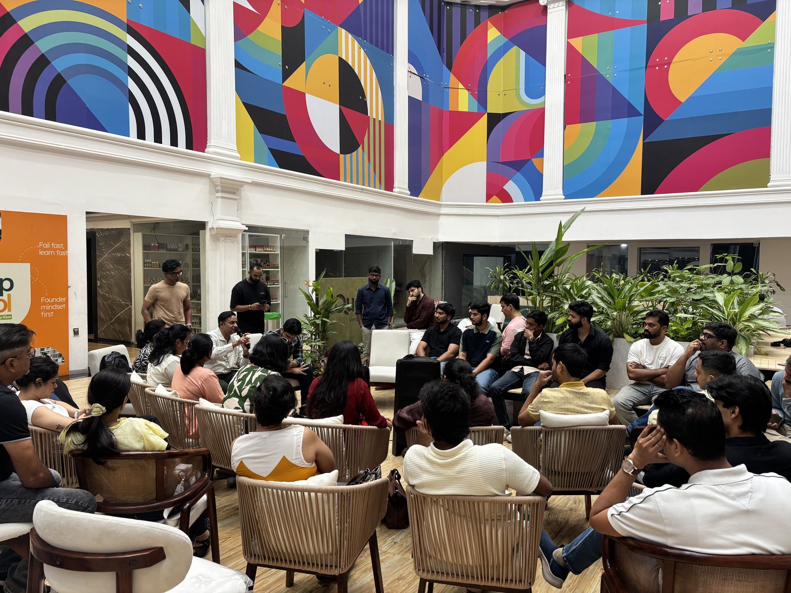 A curated networking circle at
            a past Edock meetup: two rings of founders in conversation under a large colourful
            mural.